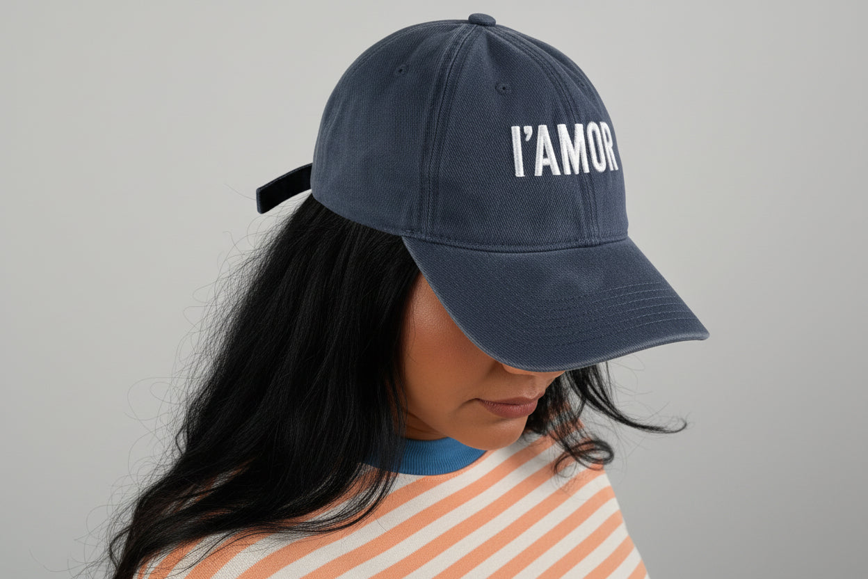 Lady wearing a striped shirt and IAMOR cap holding on a white background